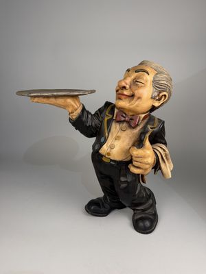 figurine représentant un vieil homme tenant un plateau, le sourire aux lèvres