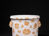 an orange and white vase with flowers on it on a black surface