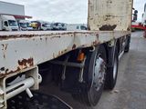 a rusted flatbed truck that is parked in a parking lot