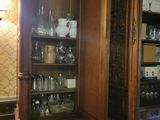 a wooden cabinet with a glass door and a clock on the wall
