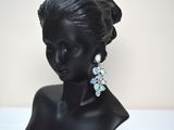 black mannequin head with blue and white earrings on it