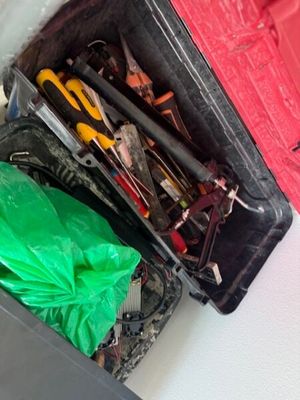 une valise rouge contenant des outils, posée par terre