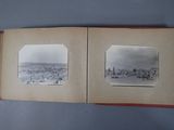 an old photo of a book opened to show a picture of a city in the distance