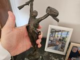 une personne tenant une statue en bronze représentant un homme tenant un marteau