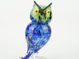 blue and green owl figurine sitting on a clear base