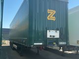 a green semi trailer parked in a parking lot