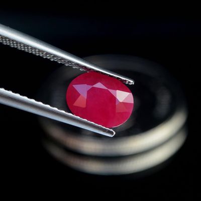 un gros plan sur une paire de pinces tenant une pierre rouge