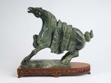 statue d'un cheval au galop posée sur un socle en bois, sur fond blanc