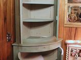 a corner cabinet with a shelf in the corner of the room