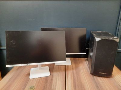 two computer monitors sitting on top of a wooden desk next to each other