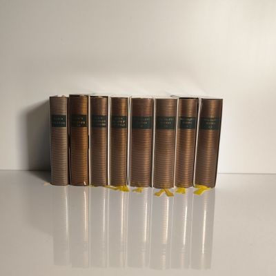 Quatre livres sont alignés sur une table devant un fond blanc.
