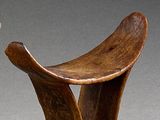 paire de tabourets en bois sculpté aux pieds courbés, posés sur un socle gris