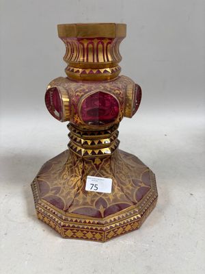 un vase doré et rouge surmonté d'un verre rouge