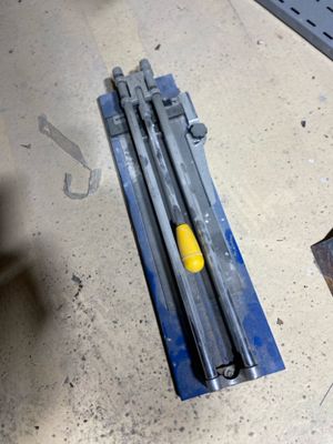 a piece of metal on the floor next to a pair of screws