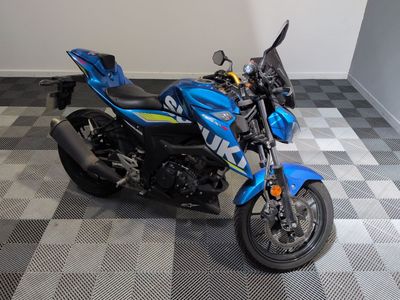 une moto bleue garée sur un sol à damier