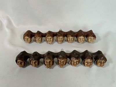 deux morceaux de bois sculptés représentant des visages, posés sur une surface blanche
