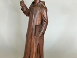 wooden statue of a monk holding a rosary in his right hand