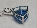 un pendentif en verre bleu muni d'une chaîne en argent, posé sur une table