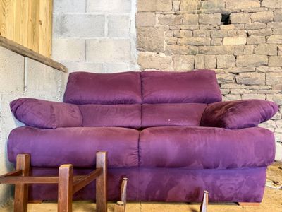 un canapé violet posé devant un mur de briques