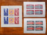 trois timbres différents posés sur une table en bois, sur laquelle figure la photo d'un homme en costume-cravate