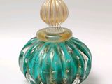 un flacon de parfum en verre vert avec un bouchon doré