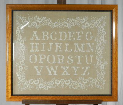 une photo d'un alphabet brodé au point de croix posé sur un chevalet