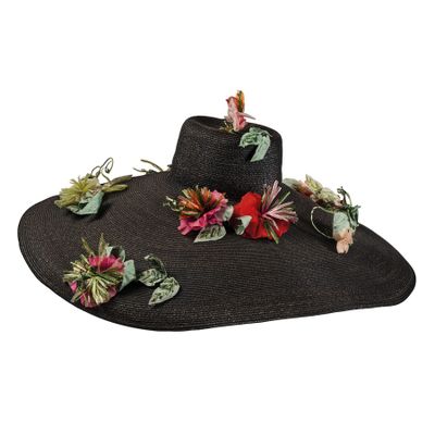 Le chapeau est noir, orné de fleurs et de feuilles.