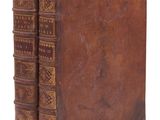 un vieux livre à la couverture brune posé sur une surface blanche