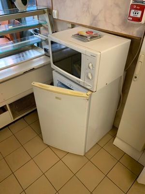 un réfrigérateur et un micro-ondes dans une cuisine au sol carrelé