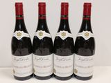 quatre bouteilles de vin rouge sont alignées sur une table