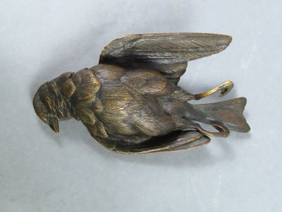 a bronze bird that is sitting on a white surface
