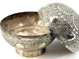 a silver bowl with a lid sitting on a white surface