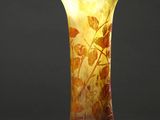 un vase orange posé sur une table blanche près d'un mur