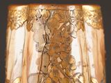a close up of a glass vase with gold flowers on it