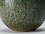 a close up of a green vase on a white surface