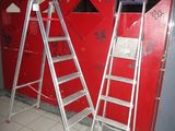 two ladders that are standing in front of a red wall