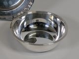 a silver bowl and a silver plate on a table