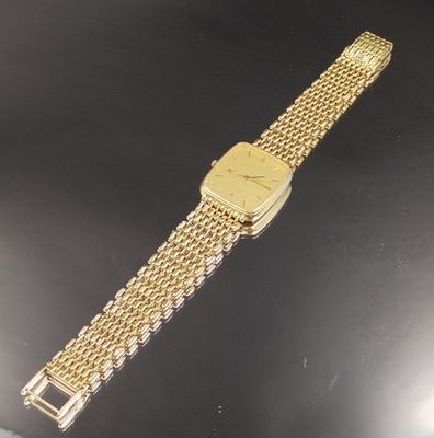 une image représentant une montre-bracelet en or posée sur une surface noire