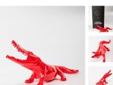 red plastic crocodile figurine with a box of chocolates in the background