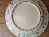 a white plate with blue designs on it sitting on a wooden table