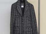 a black and white tweed jacket hanging on a clothes rack