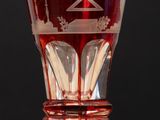 un verre rouge posé sur une table en bois, sur fond noir