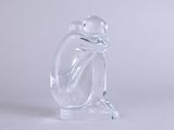 une figurine en verre représentant une grenouille assise sur un socle