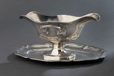 une saucière en argent posée sur un plateau en argent, sur une table