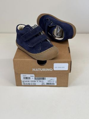 des chaussures bleues de petit garçon dans une boîte posée sur une surface blanche