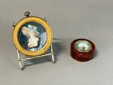 a miniature picture of a woman in a hat next to a small wooden box