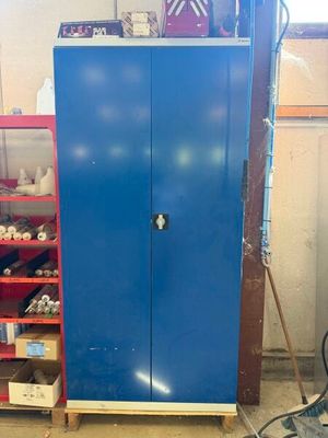 une armoire bleue dans un garage, avec des outils sur les étagères