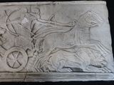 a stone relief of a man on a horse drawn carriage