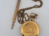a gold pocket watch and a pen on a white surface