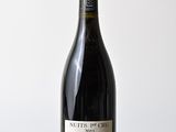 the bottle of wine is sitting on a wooden table